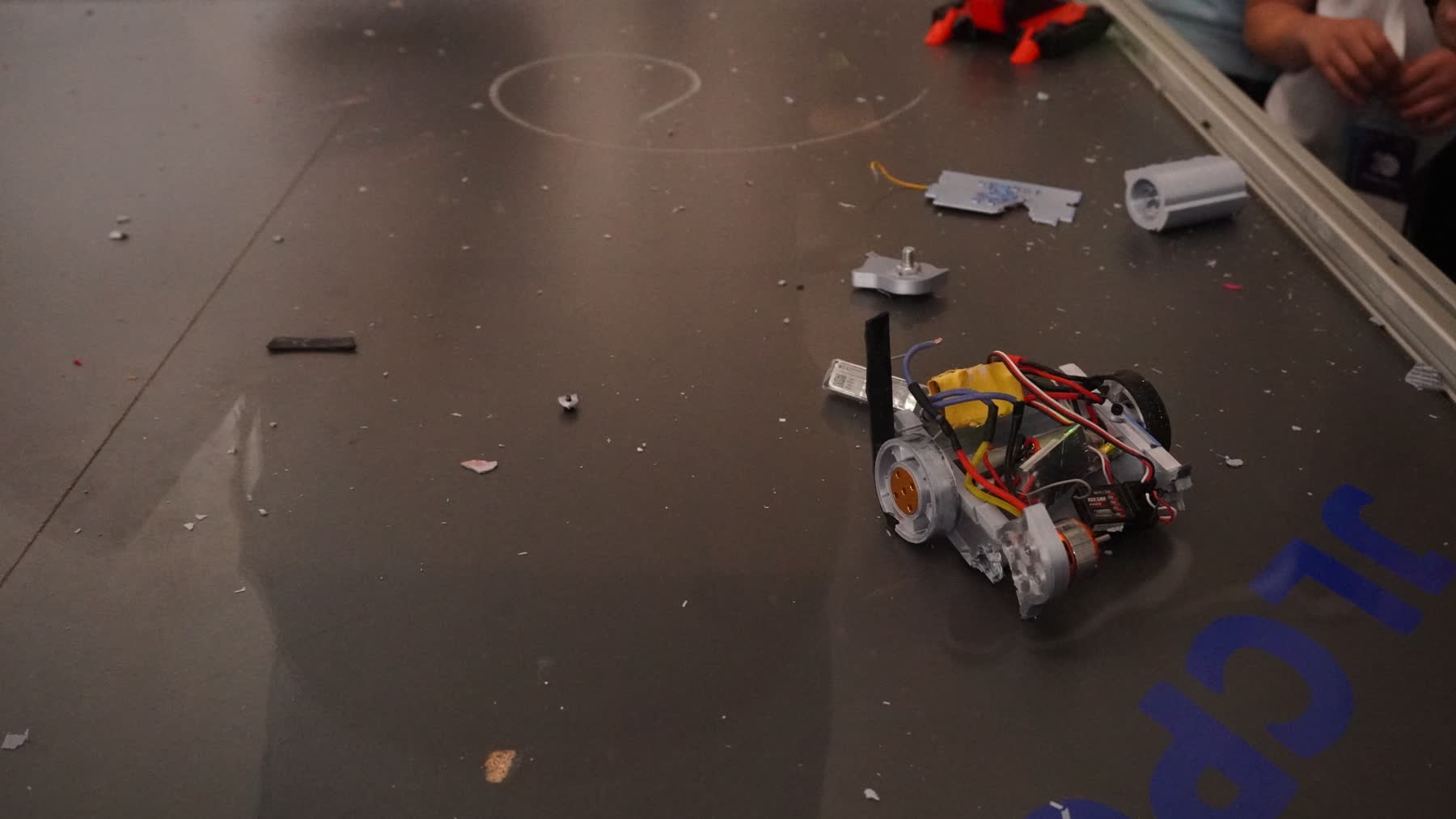 Vista en picado de la arena con un robot dañado y restos por el suelo